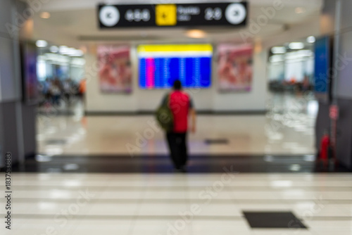 Man walking down the interior hallway of an airport terminal. Blurred image. Background.