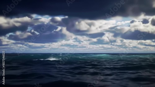 A vast, dark ocean under a sky filled with soft, gray-tinged clouds casting shadows on the water