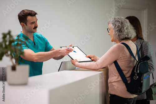 Canvas Print Medical professional handing clipboard for patient check-in