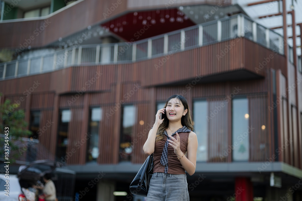 Fototapeta premium Woman smiling talking on phone in modern city street