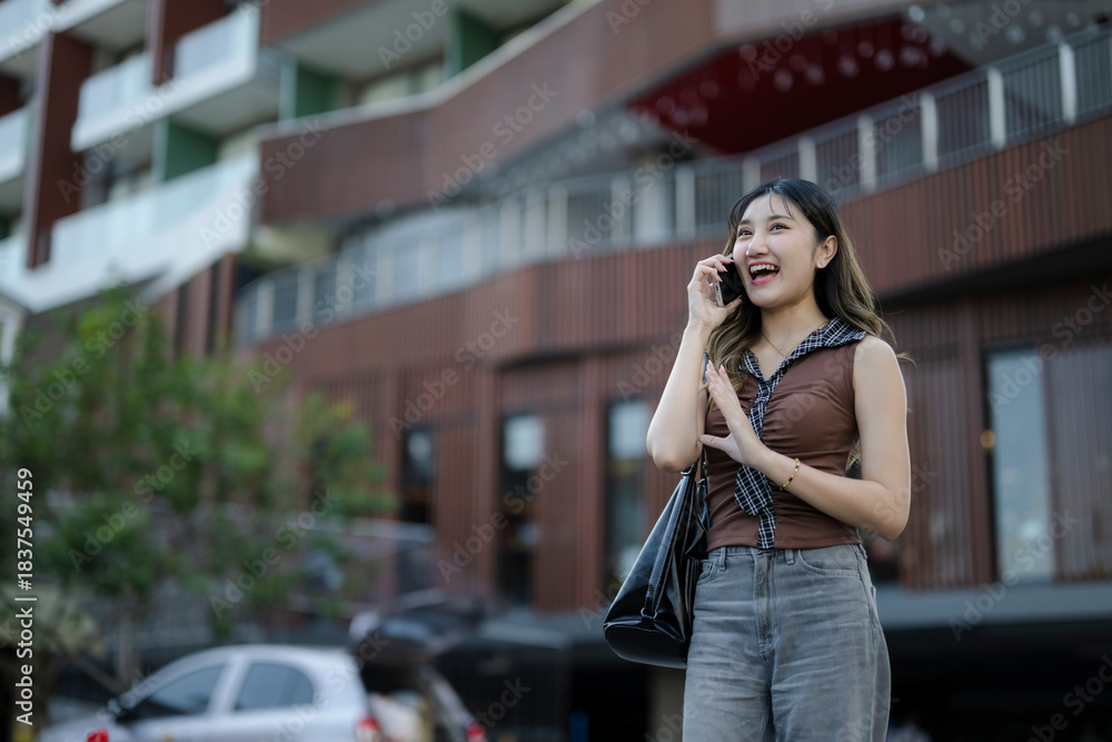 Fototapeta premium Young woman smiling enjoying mobile phone conversation in city