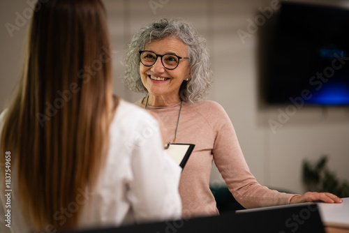 Senior woman smiling offering customer service at reception