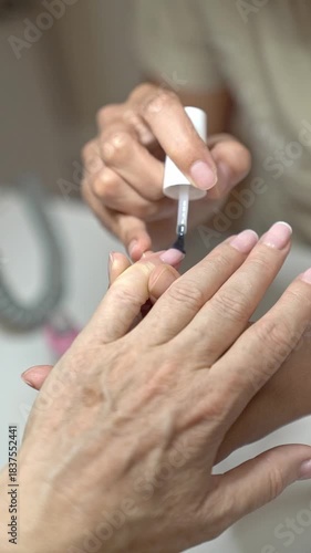 Close up of Classic French Manicure Process on Mature Hands With Modern Tools. Application base coat transparent coating