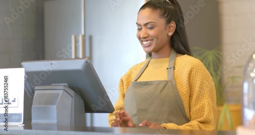 Mid Adult barista in apron recognizing customer at counter, tapping register and confirming order