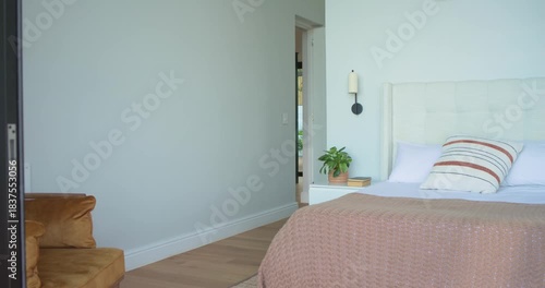 On clip start camera is panning past sliding glass door and armchair to reveal bedroom layout