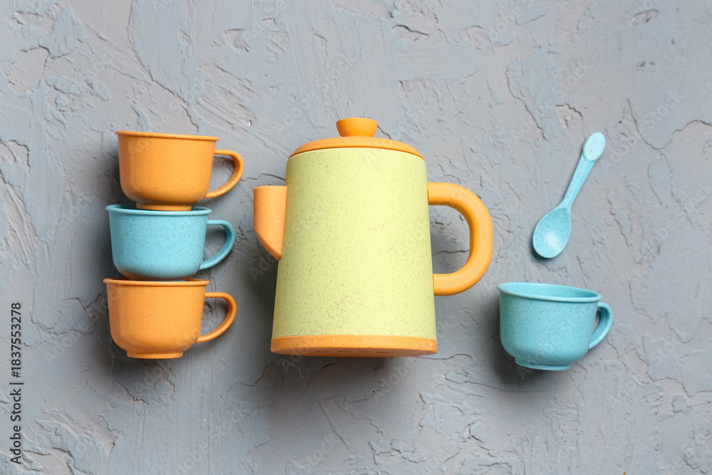 Fototapeta premium Teapot with cups and spoon for baby on grunge grey background