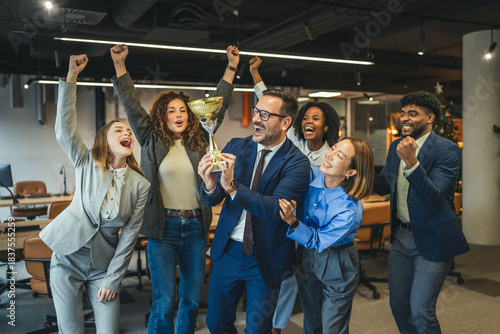 Foto Diverse business team celebrating achievement and success holding trophy