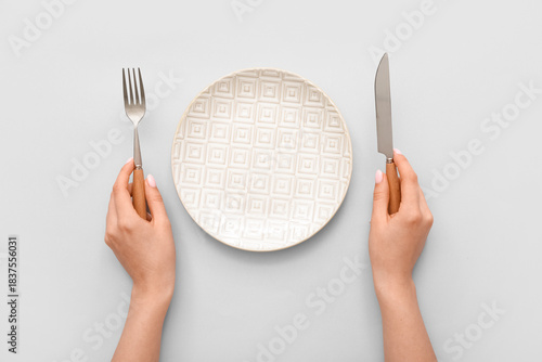 Tableau sur toile Woman with cutlery and empty plate on grey background