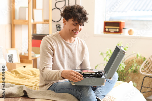Young man with record player in bedroom