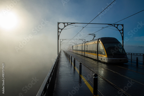 Obraz na plátně Tram on Luis I bridge emerging from the fog shrouding a church tower in Porto, P