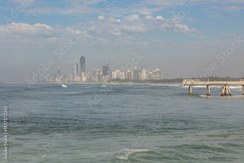 Surfers Paradise, the most developed section of the Gold Coast, seen in a sea haze across the sea from the Seaway, against a blue sky with clouds background on the Gold Coast in Queensland, Australia.