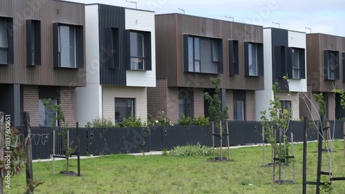 Modern two-storey townhouses in an outer suburb of Melbourne, Australia, featuring contemporary facades and overlooking green public space with young trees. A growing outer-metro neighbourhood