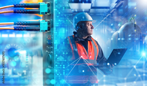 Bild auf Leinwand Industrial network technician monitors digital infrastructure with a laptop, inspecting connected systems, analyzing data flow and ensuring reliable communication between automated equipment