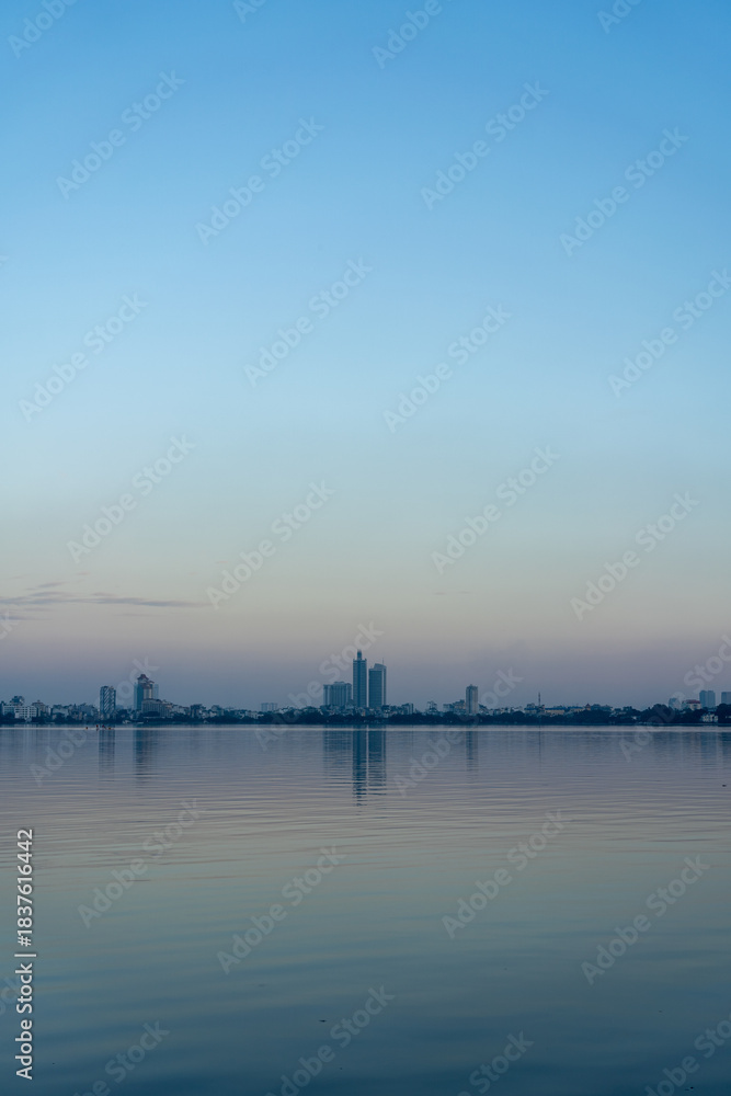 Naklejka premium Skyline of Hanoi Reflected on Hồ Tây (West Lake) at Dusk, Vietnam