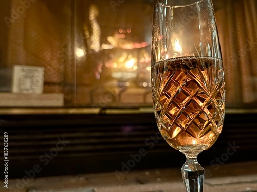 Close-up of champagne glass with fireplace behind