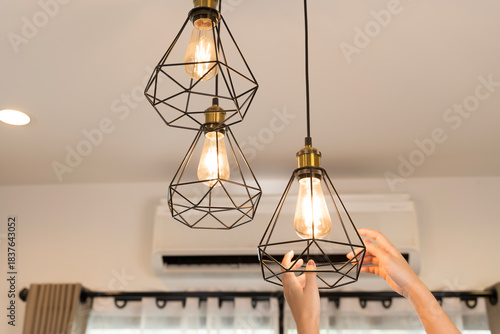 Hands adjusting pendant light bulbs modern home interior lighting decoration energy design idea stylish living