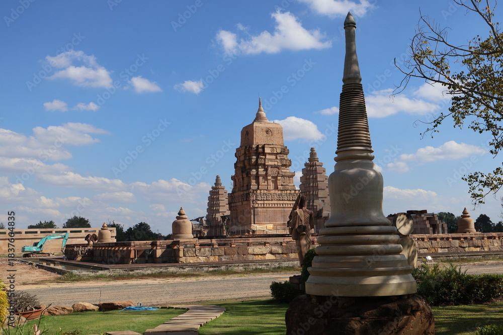 Obraz premium A serene temple complex in Myanmar. Dominating the center of the image is a large pagoda with multiple tiers, its golden surface catching the sunlight