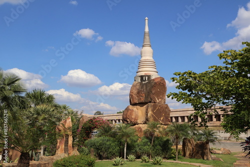 A tall building with a pointed structure at the top, possibly a temple or a museum, surrounded by greenery