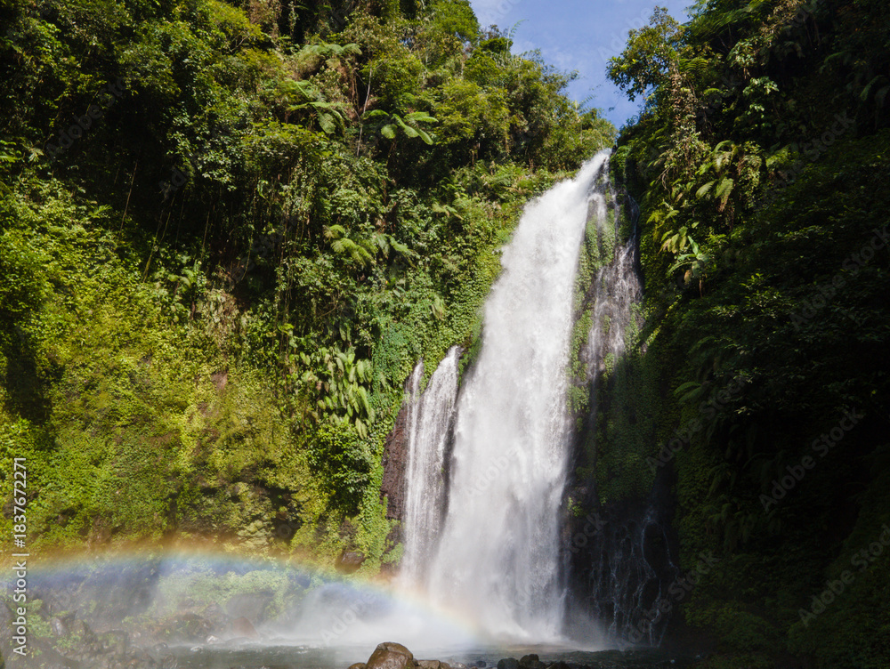 Fototapeta premium Aerial view of Gomblang Waterfall with Rainbow in Lush Forest, Java Island, Indonesia