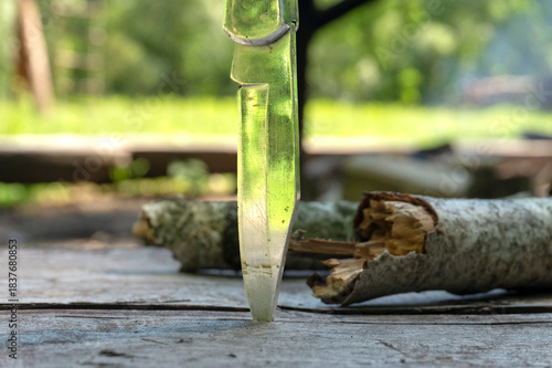 Close-Up of Fixed Blade Knife Stabbing Wood on Outdoor Wooden Surface in Natural Light Outdoors