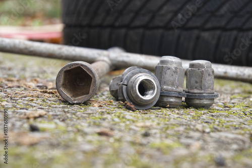 Close up of lug nuts and a wrench on a concrete surface