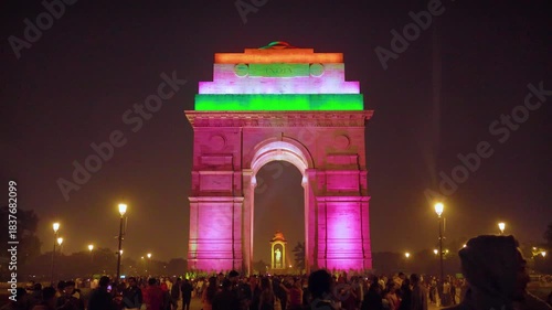 Delhi, India, November 28, 2025. Visitors walk toward India Gate illuminated with tricolor lights along Kartavya Path during a busy evening