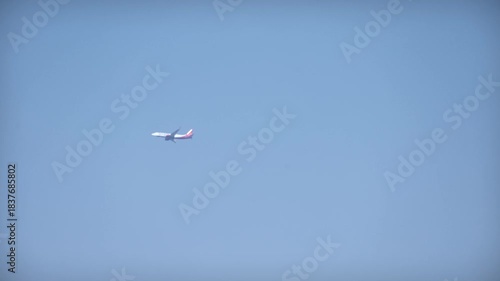 Passenger airplane flying across a clear blue sky captured from the ground with ample copy space.