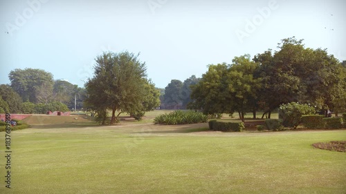 Delhi, India, November 28, 2025. A manicured green lawn with trees and landscaped shrubs inside the public garden complex surrounding the Lotus Temple in New Delhi.