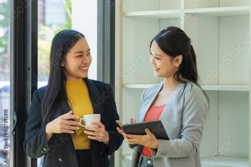 Portrait of two young businesswomen having a meeting or presentation and seminar standing in the office. Portrait of a young businesswoman talking.