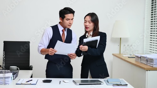 Two  Asian businessman and woman workers talking on the smartphone and using laptop Professionals in Teamwork Finance, Marketing, and Success at the office.