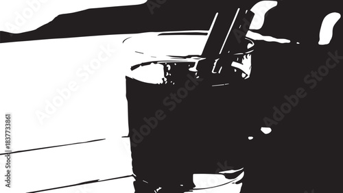 Close up high contrast glass of beverage with straw on table.