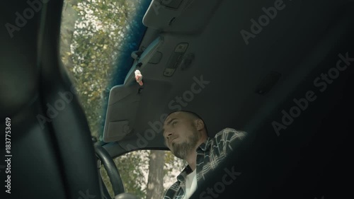A sad man is sitting in a car. An expression of annoyance, anxiety and worry. 