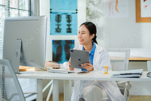 Asian female doctor consultation or tell patients the results of examinations by mobile phone and holding tablet at clinic hospital.Concept of telemedicine,remote consultation and modern healthcare