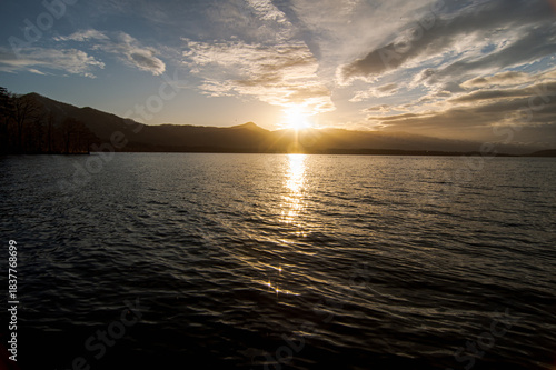 Wallpaper Mural 風に吹かれた湖の日暮れの場面。さざ波の水面に太陽光が反射し空にはドラマチックな雲の模様。 Torontodigital.ca