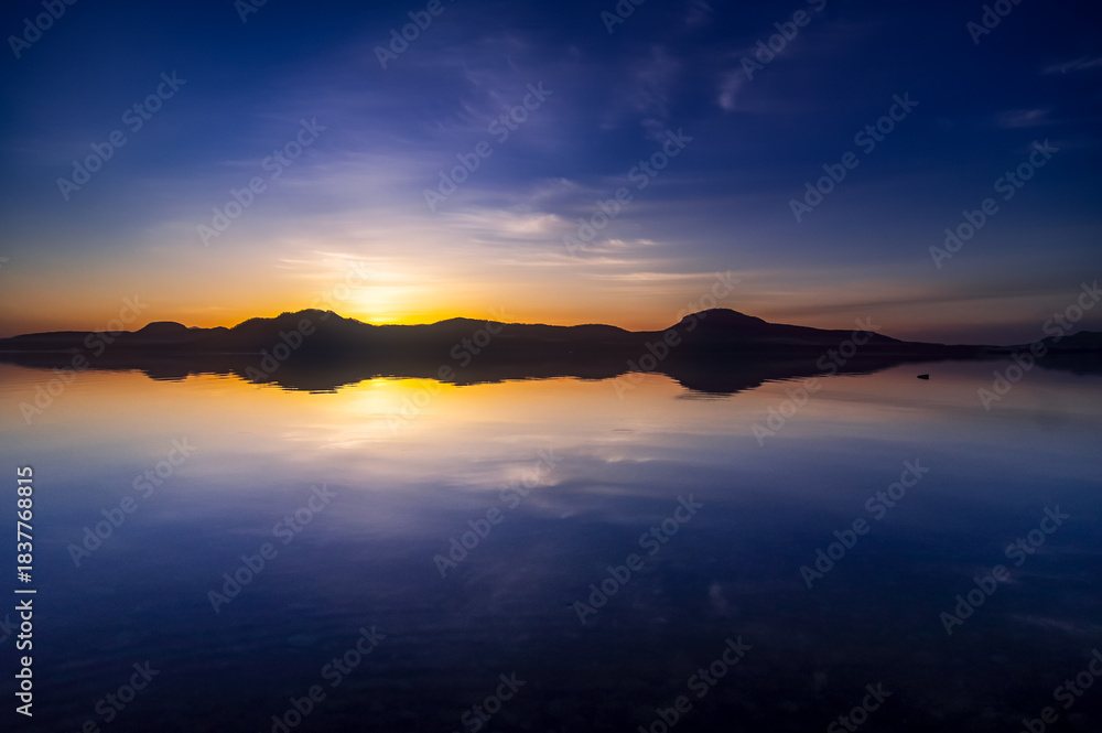 Fototapeta premium 深い青の空が水面に反射する湖の劇的な風景。
