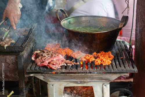 Outdoor street food preparation with grilled meat and nopal cactus