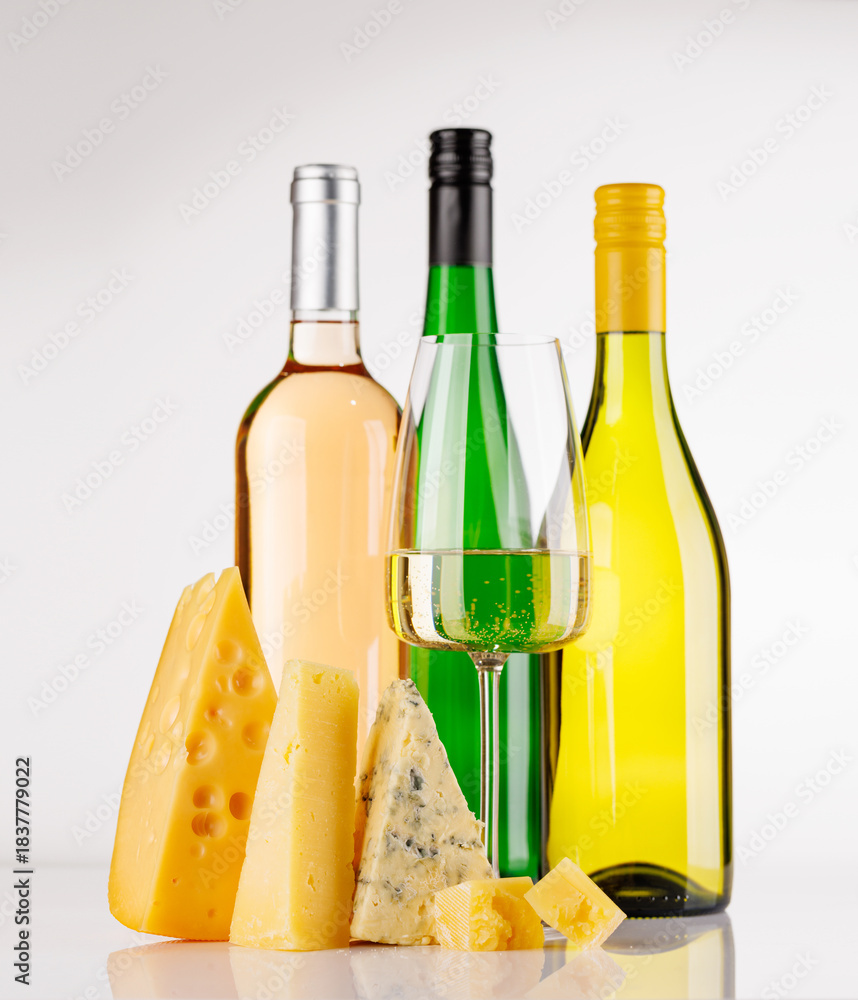 Naklejka premium Assorted cheeses and wine bottles on white background