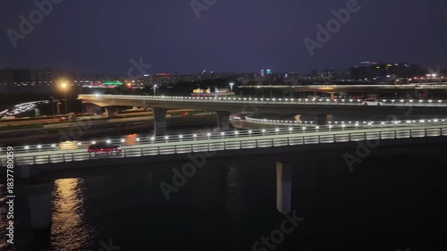 Illuminated Highway Bridge Over Water at Dusk with Traffic and City Lights