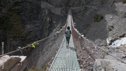 High Altitude Trekking Solo Traveler on Prayer Flag Bridge at Annapurna circuit trek on the way to Tilicho lake.