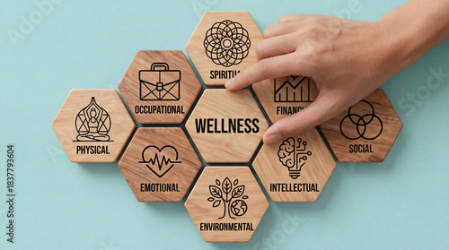 Hand placing the 'Wellness' tile at the center of eight interconnected hexagonal blocks representing the comprehensive dimensions of holistic health and well-being