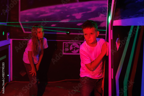 Girl and boy playing a laser labyrinth simulation game. Interactive adventure room.