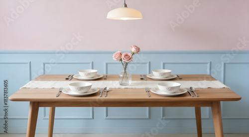 Wooden dining table setting with pink roses, floral tableware, and pastel wall paneling. Modern interior design featuring blue wainscoting, light wood furniture, and minimalist decor.