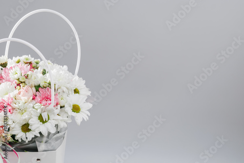 Fototapeta Naklejka Na Ścianę i Meble -  A beautiful bouquet of daisies, peonies, and roses in a white cardboard box. Light background. Banner. Space for your text.