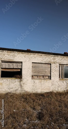 an old abandoned building made of brick in the winter, an abandoned building for demolition, the entrances and windows to the building are boarded up