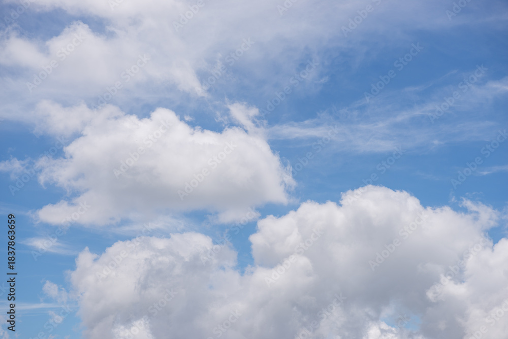 Obraz premium A blue sky filled with fluffy white clouds. Background.