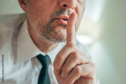 Tableau sur toile Professional man in formal attire holding a finger to his lips, expressing secrecy or confidentiality