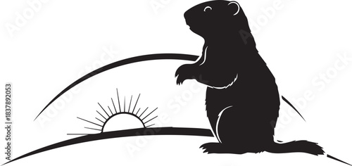 Silhouette of a groundhog standing and looking at a rising sun on a hill