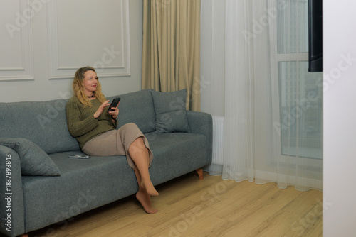 Woman sitting on a couch engaging with her phone while enjoying indoor evening