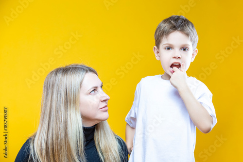 Smiling Cheerful Happy Couple Woman And Child Boy In Casual Clothing Having Mommy Little Kid Son Hug Cuddle While Showing His Teeth Looking Straight on Yellow To Convey Mother's Love Day