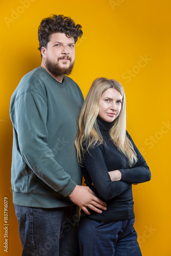 Portrait of Young Positive Caucasian Smiling Happy Adorable Couple As Friendly Family Man And Woman Casual Clothing Together Hugging Embracing Cuddle Isolated on Yellow Background